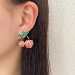 Pink and green crystal cherry stud earrings in gold alloy, shown on a female model