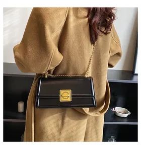 Detail of black leather square bag with gold hardware buckle and elegant chain strap
