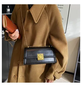 Close-up of black PU leather shoulder bag with vintage gold square lock and chain strap