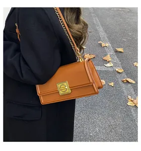 Close-up of caramel rectangular crossbody bag with gold square buckle and chain strap