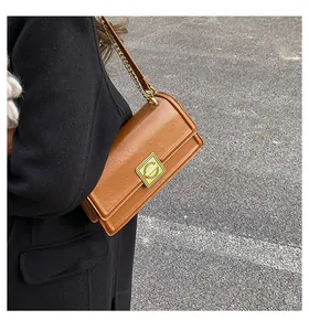 Brown retro flap crossbody bag with golden metal buckle and chain strap on a model