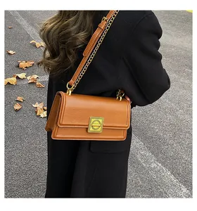 Close-up of brown leather crossbody bag with gold ring buckle and chain strap detailing