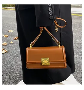 Detailed view of caramel leather texture and gold square clasp on retro shoulder bag