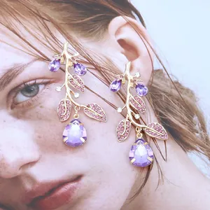 Golden branch earrings with purple crystals and pink rhinestones on a female model