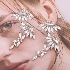 Macro shot of large golden leaf earrings with sparkling marquise crystal inlay