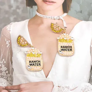 Détail de boucles d'oreilles bouteille avec perles, texte Ranch Water et citrons