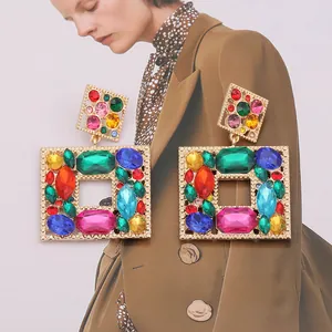Close-up of geometric square drop earrings with vibrant multi-colored crystal stones