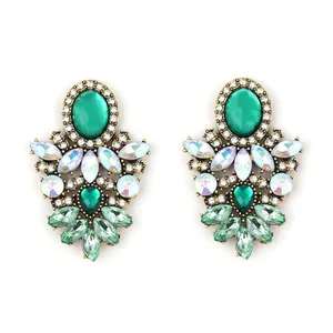 Macro shot of bohemian vintage earrings with emerald green crystals and gold alloy settings