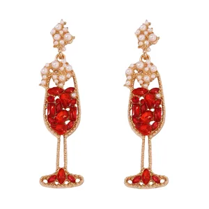 Detailed view of wine glass earrings with red rhinestones and faux pearls in gold
