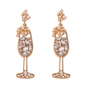 Macro detail of wine glass shaped earrings with pearls and sparkling rhinestones