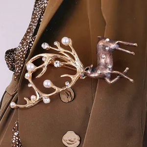 Detalle de un broche de alce dorado con perlas y pedrería sobre tela texturizada