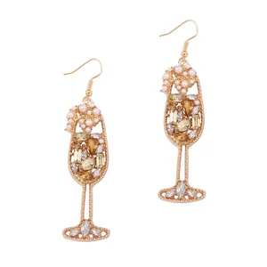 Detail of gold champagne glass earrings with faux pearls and sparkling amber crystals