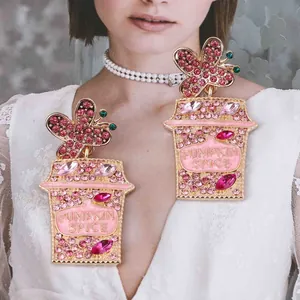 Close-up of pink butterfly coffee cup earrings with Pumpkin Spice lettering and crystals