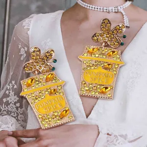 Detail of butterfly and coffee cup drop earrings with yellow rhinestones and Pumpkin Spice text