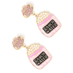 Boucles d'oreilles tasse en émail rose avec perles et cristaux sur fond blanc pur