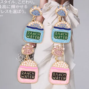 Détail de boucles d'oreilles en émail rose et bleu avec perles et strass colorés