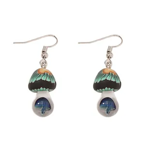 Detail of mushroom earrings with black cap, green stripes, and blue mushroom inside a clear bead