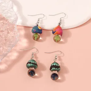 Handmade mushroom earrings featuring colorful polymer clay designs and glass pendants