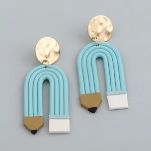 Macro shot of colorful handmade clay pencil earrings with gold hammered metal studs