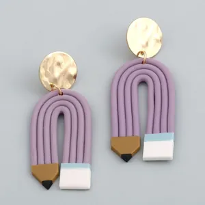 Creative pencil shaped polymer clay earrings with gold metallic discs on light gray background