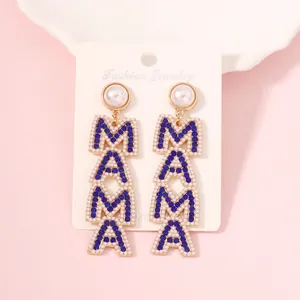 Golden MAMA drop earrings with blue rhinestones and white pearls on display card