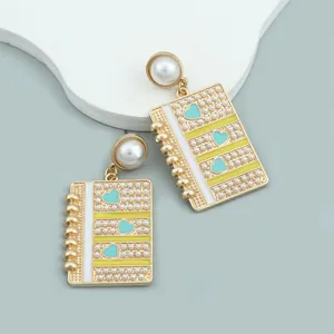 Chic notebook earrings with blue enamel hearts and faux pearl inlay on a gold base