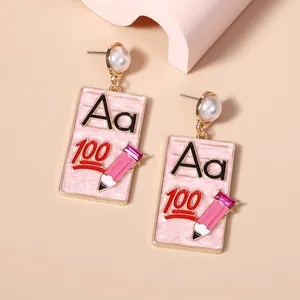 Detail of pink geometric drop earrings featuring pencils and Aa letter patterns