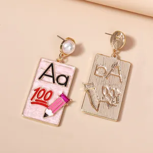 Detail of pink enamel earrings with pencil, Aa letters and 100 on golden metal base