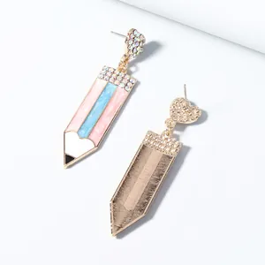 Detalle de pendientes de lápiz con esmalte colorido, diamantes y dorso de metal cepillado
