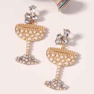 Detailopname van gouden cocktailglas oorbellen met parels en kristallen accenten