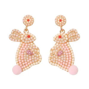 Zoete roze konijnen oorbellen met crème kralen en pompoms in gouden zetting
