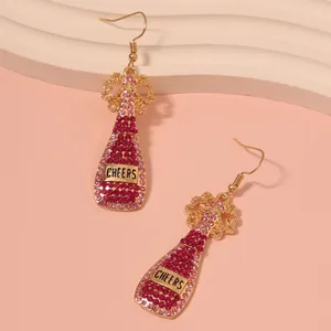 Macro detail of wine bottle drop earrings with pink rhinestones and 'CHEERS' label