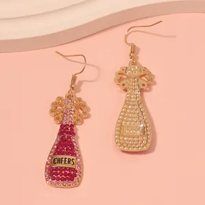 Close-up of champagne bottle earrings with pink rhinestones and Cheers engraving