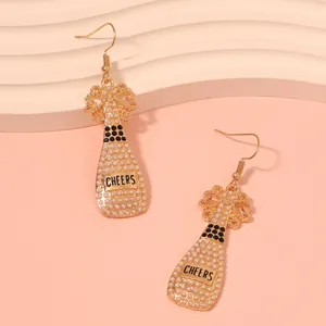 Detail of champagne bottle earrings with white pearls and cheers lettering in gold