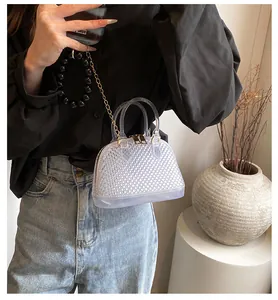 Detail of transparent holographic shell bag with diamond texture and gold chain strap
