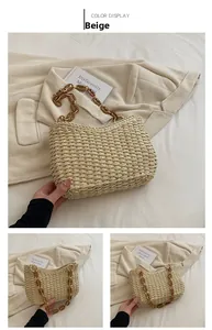 Detalle del bolso de paja tejida con correa de cadena ámbar sobre tela con textura