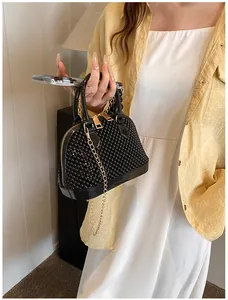 Detail of black shell-shaped beaded bag with golden chain and pearl texture