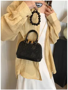 Close-up of black beaded shell bag with gold zipper and chain strap on a model
