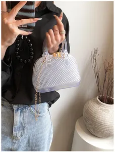 Detail of transparent PVC jelly shell bag with gold zippers and metal chain strap