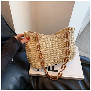 Detalle del bolso bandolera de paja tejida con cadena de acrílico marrón y hebilla dorada