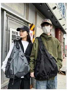 Outdoor street style view of high-capacity black tactical nylon crossbody bag with wide straps