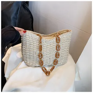 Detalle de bolso de paja tejido a mano con cadena de acrílico ámbar y anillos de metal