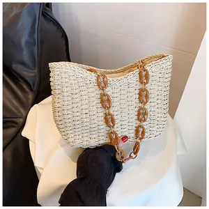 Detalle del bolso bandolera de paja con cadena de resina marrón y cierre de cremallera
