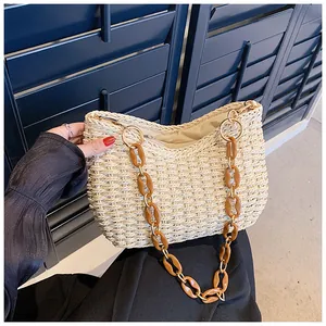 Detalle de bolso de paja tejido con cadena de acrílico ámbar y eslabones de metal