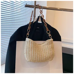 Detalle de bolso bandolera de paja con correa de hombro de resina y cadena dorada