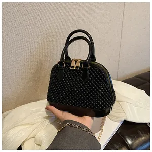 Close-up of black shell-shaped bag with pearl beads, golden zipper and chain strap