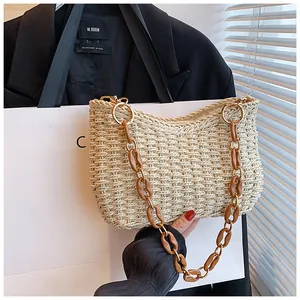 Detalle de bolso de paja con cadena de resina marrón y hebilla metálica dorada