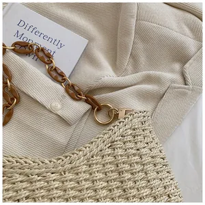 Detalle del bolso de paja beige con cadena de resina marrón y aros metálicos