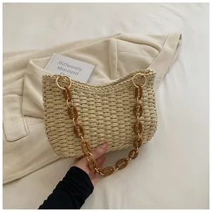 Detalle de la correa de cadena de resina ámbar en un bolso de paja trenzada