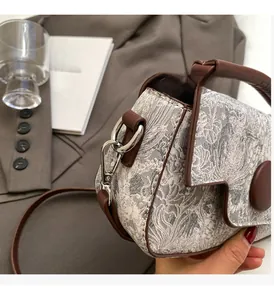 Close-up of floral tapestry bag with brown leather trim and high-shine silver metal hardware